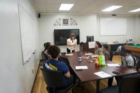 Mental health counselor talking to students around a table.